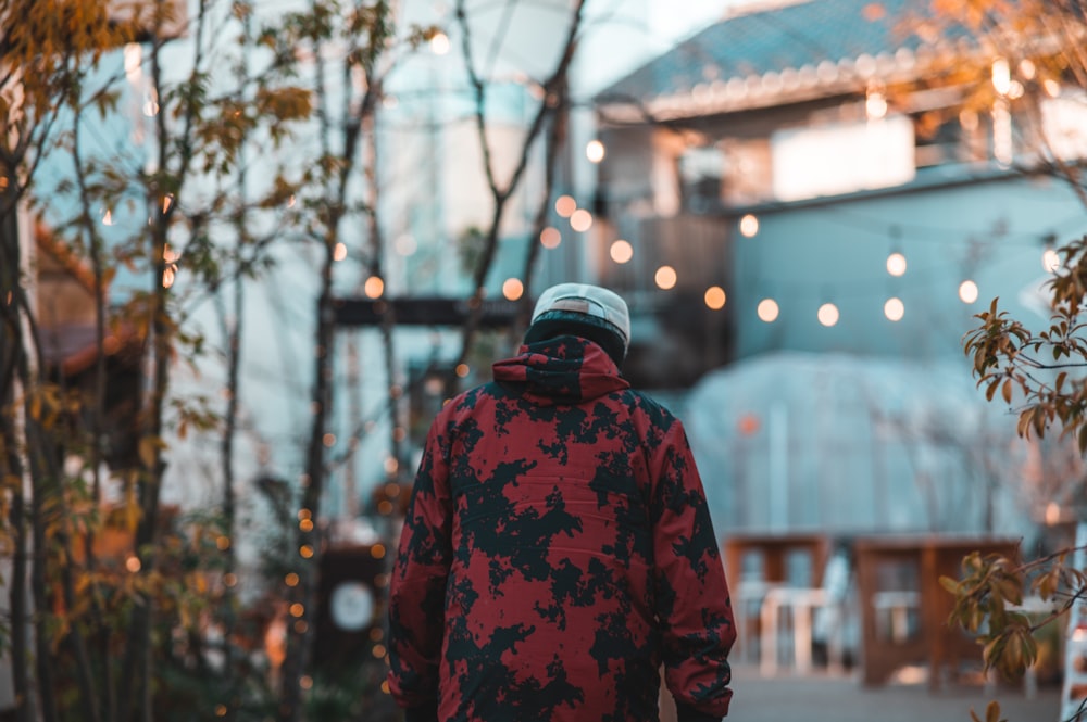 a man in a red and black jacket walking down a sidewalk