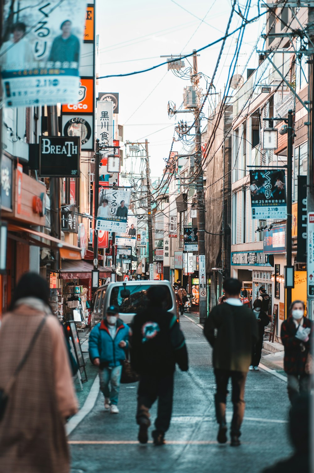 a group of people walking down a street next to tall buildings