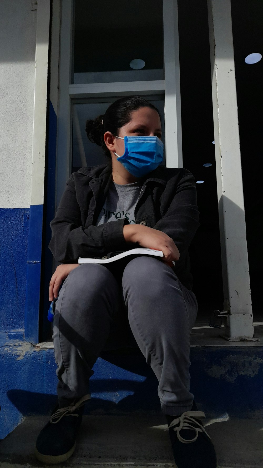 a woman sitting on a step wearing a face mask