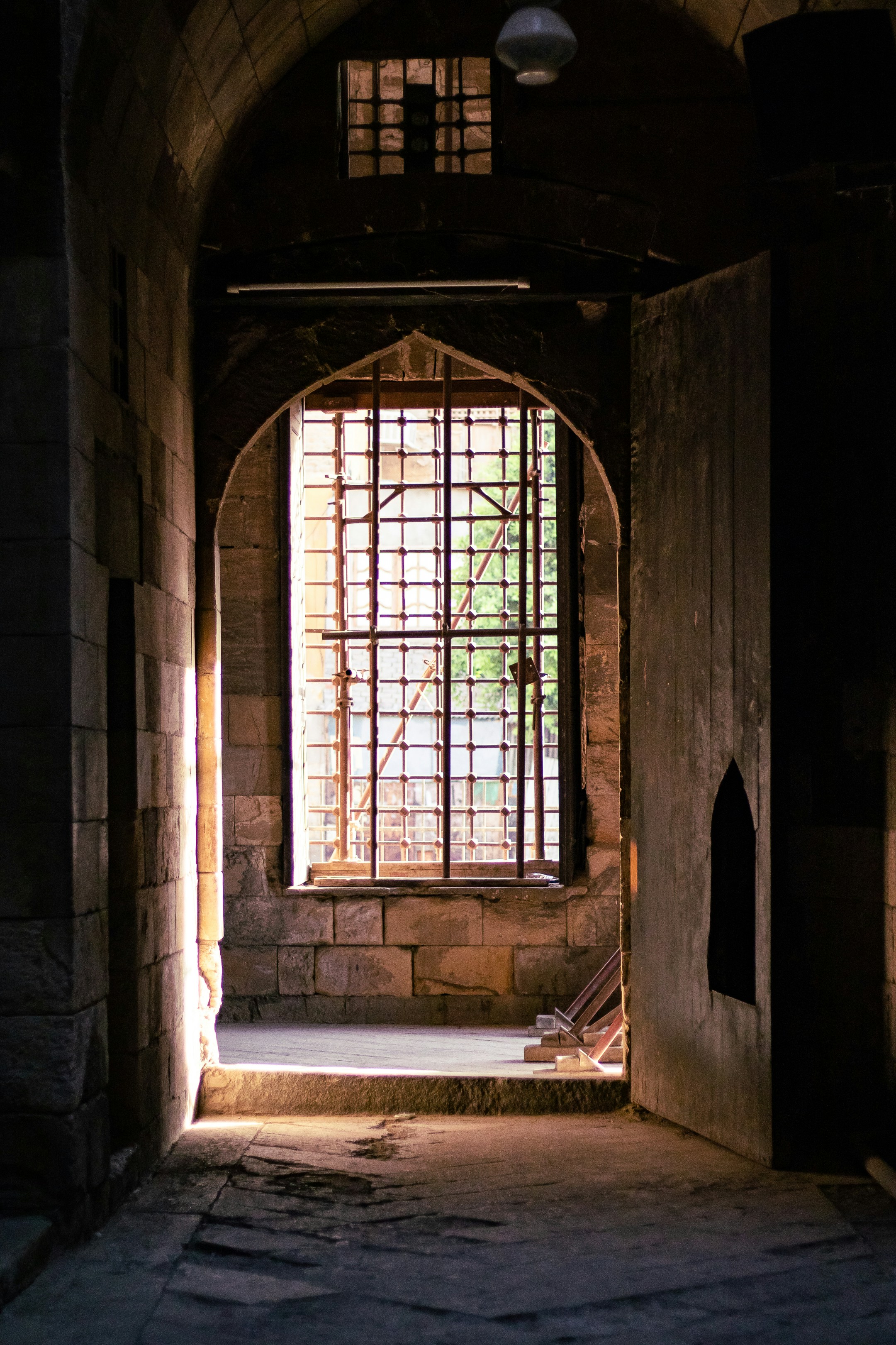 a window in a stone building with bars on the windowsill