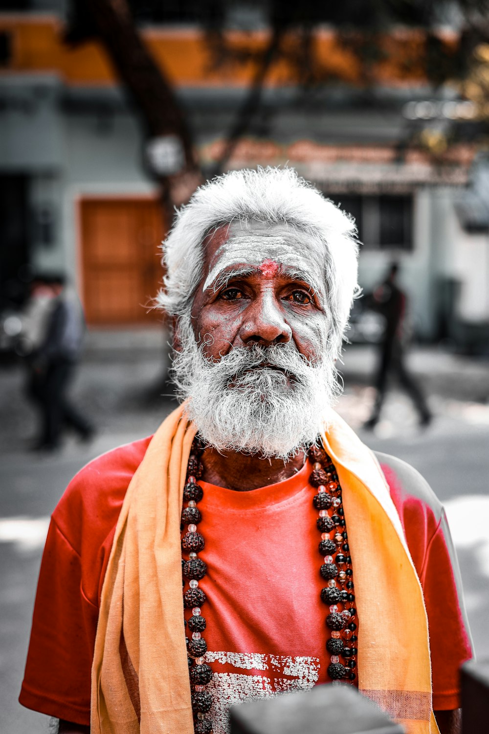 a man with a white beard and orange scarf