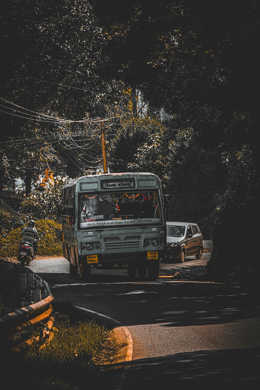 a bus driving down a street next to a forest