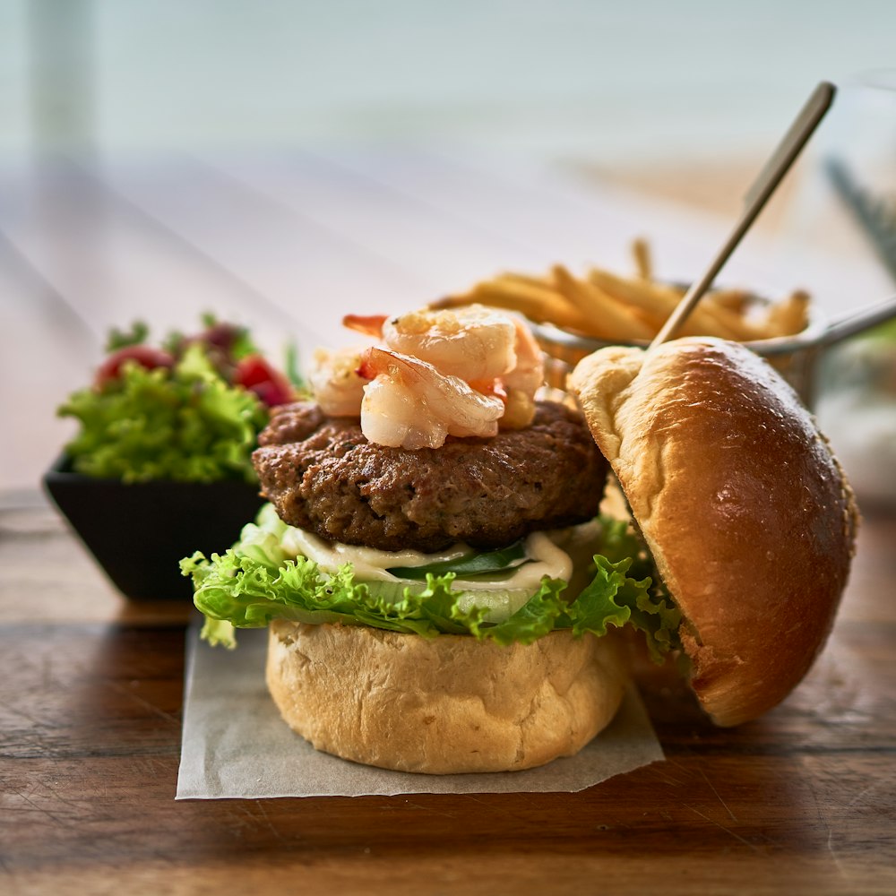 a hamburger with shrimp and lettuce on a bun