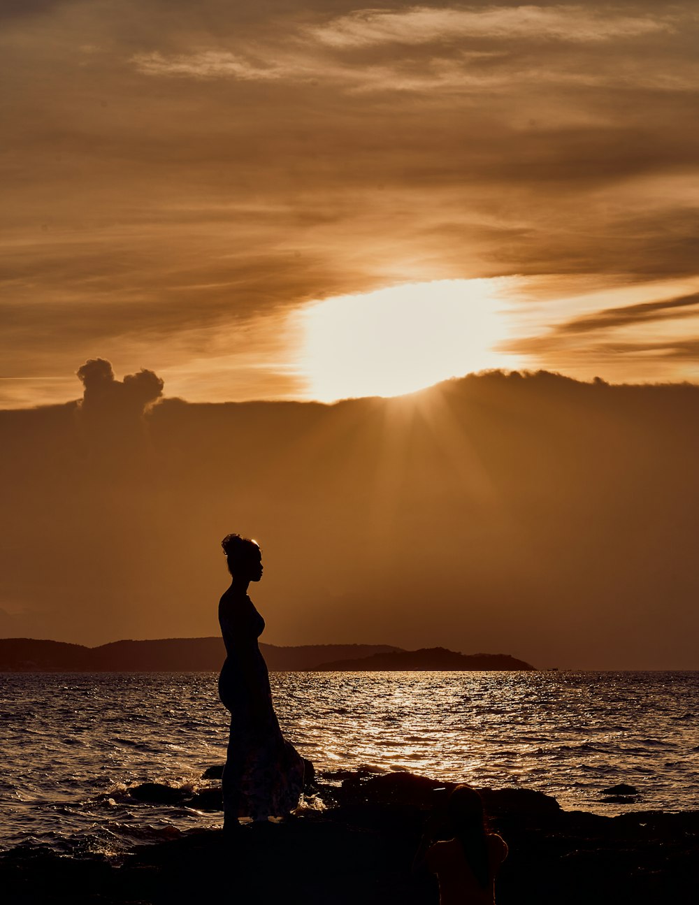 Eine Frau steht an einem felsigen Strand am Meer