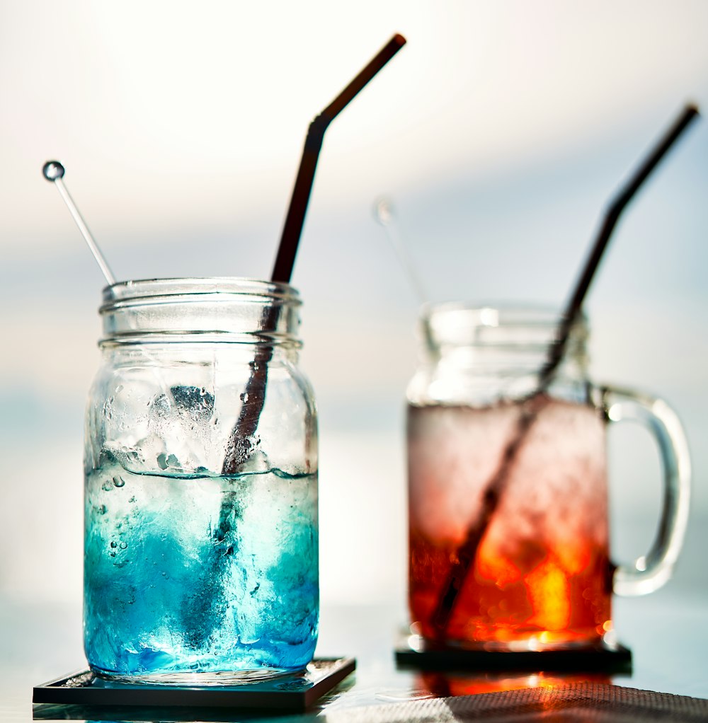 a couple of glasses filled with liquid and drinking straws