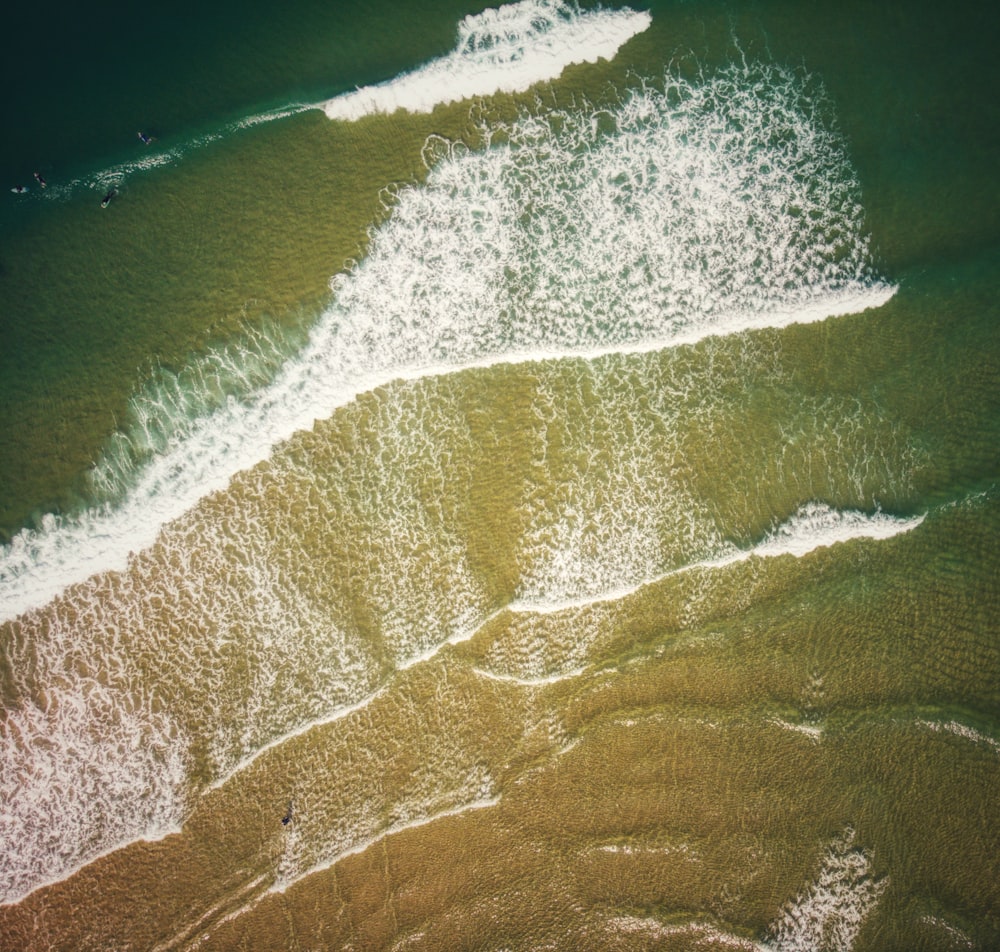 an aerial view of a beach with a wave coming in