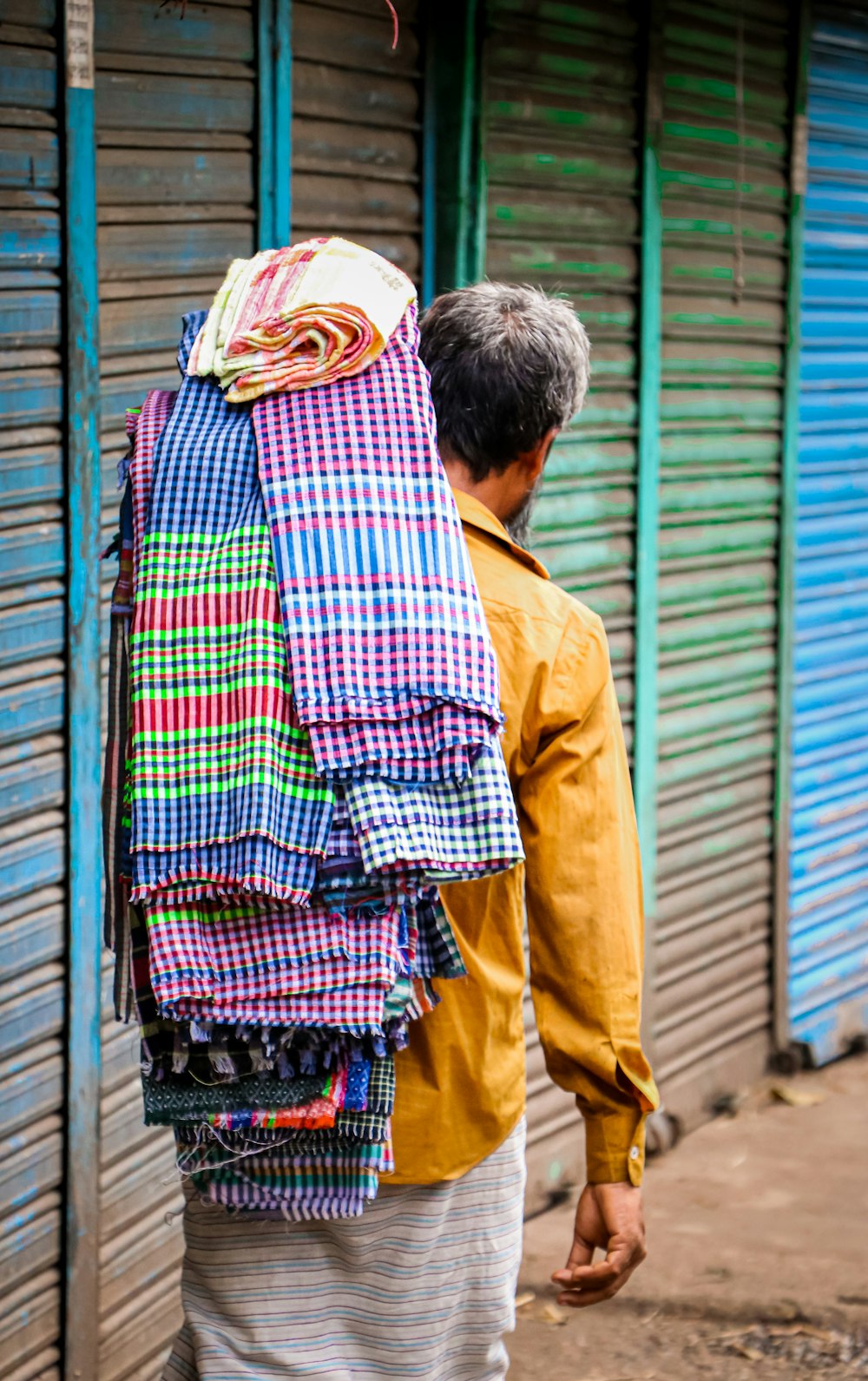 a man carrying a large stack of shirts on his back