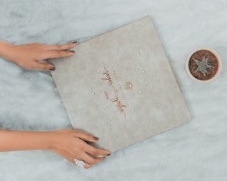 a woman's hands holding a wedding ring next to a box