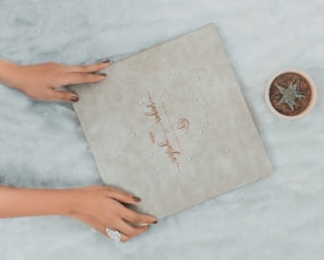 a woman's hands holding a wedding ring next to a box