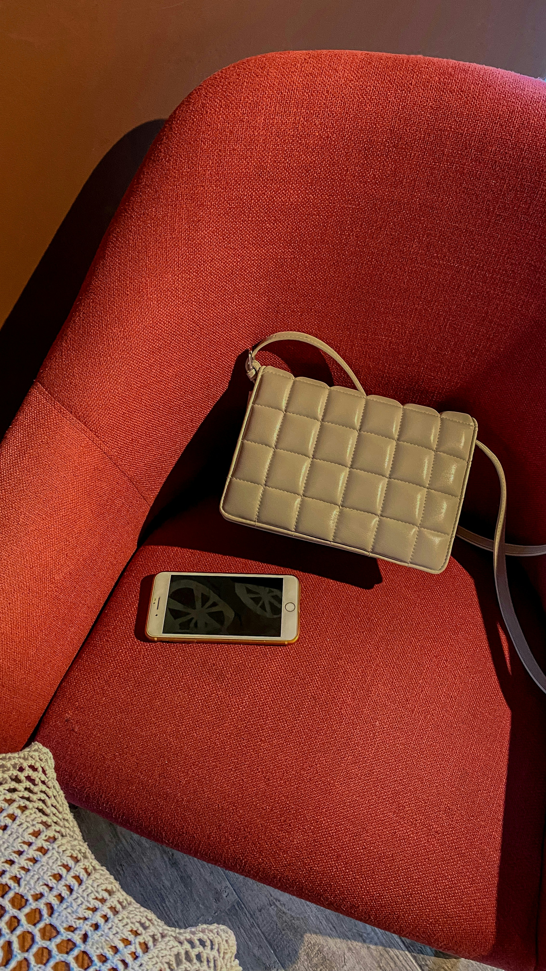 Fashionable minimalistic gray bag on red armchair with a smartphone.