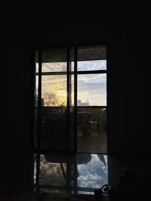 Wide view of a patio with multiple sliding glass doors reflecting the sunset.