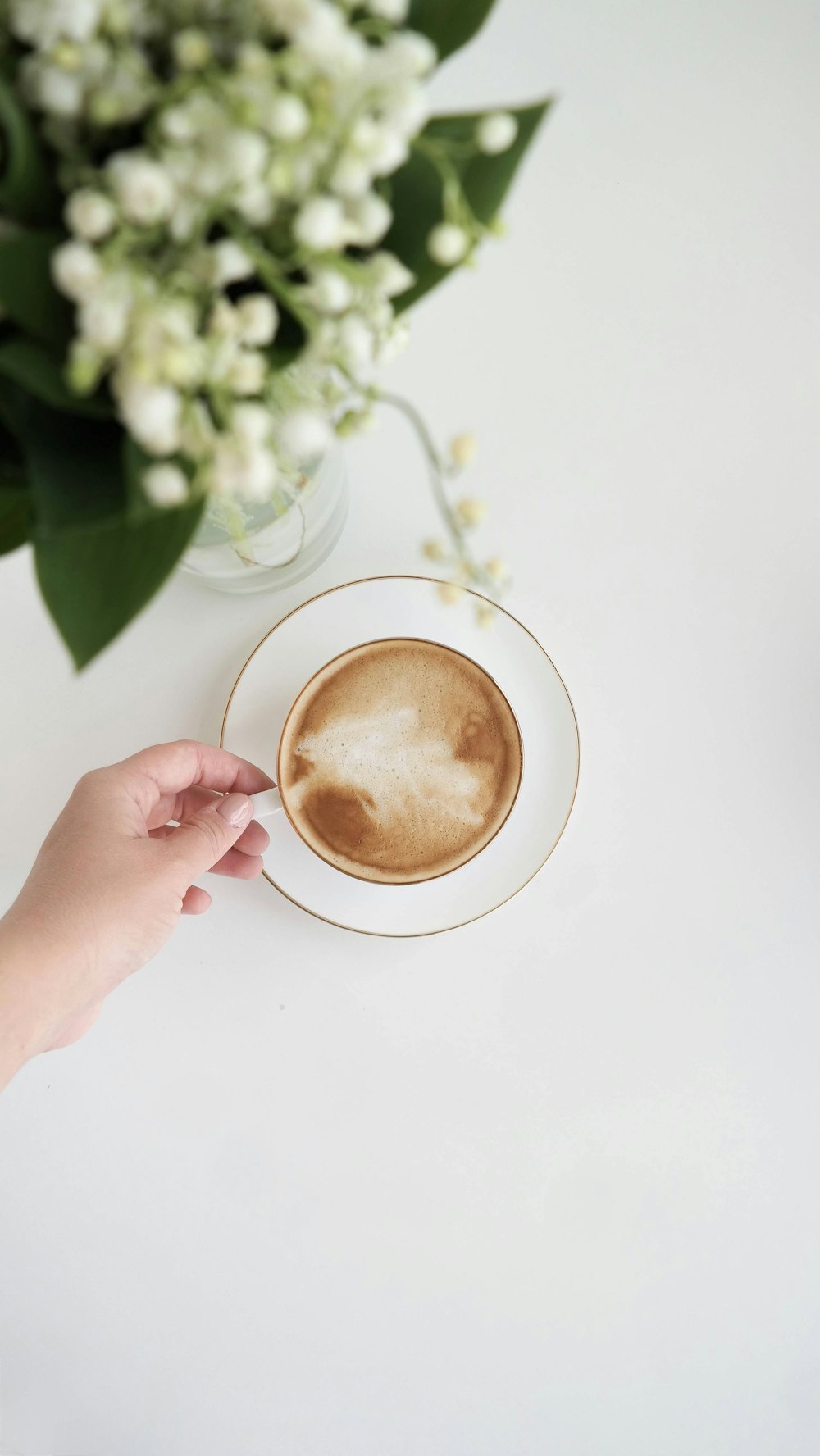 a cup of coffee on a saucer next to a vase of flowers