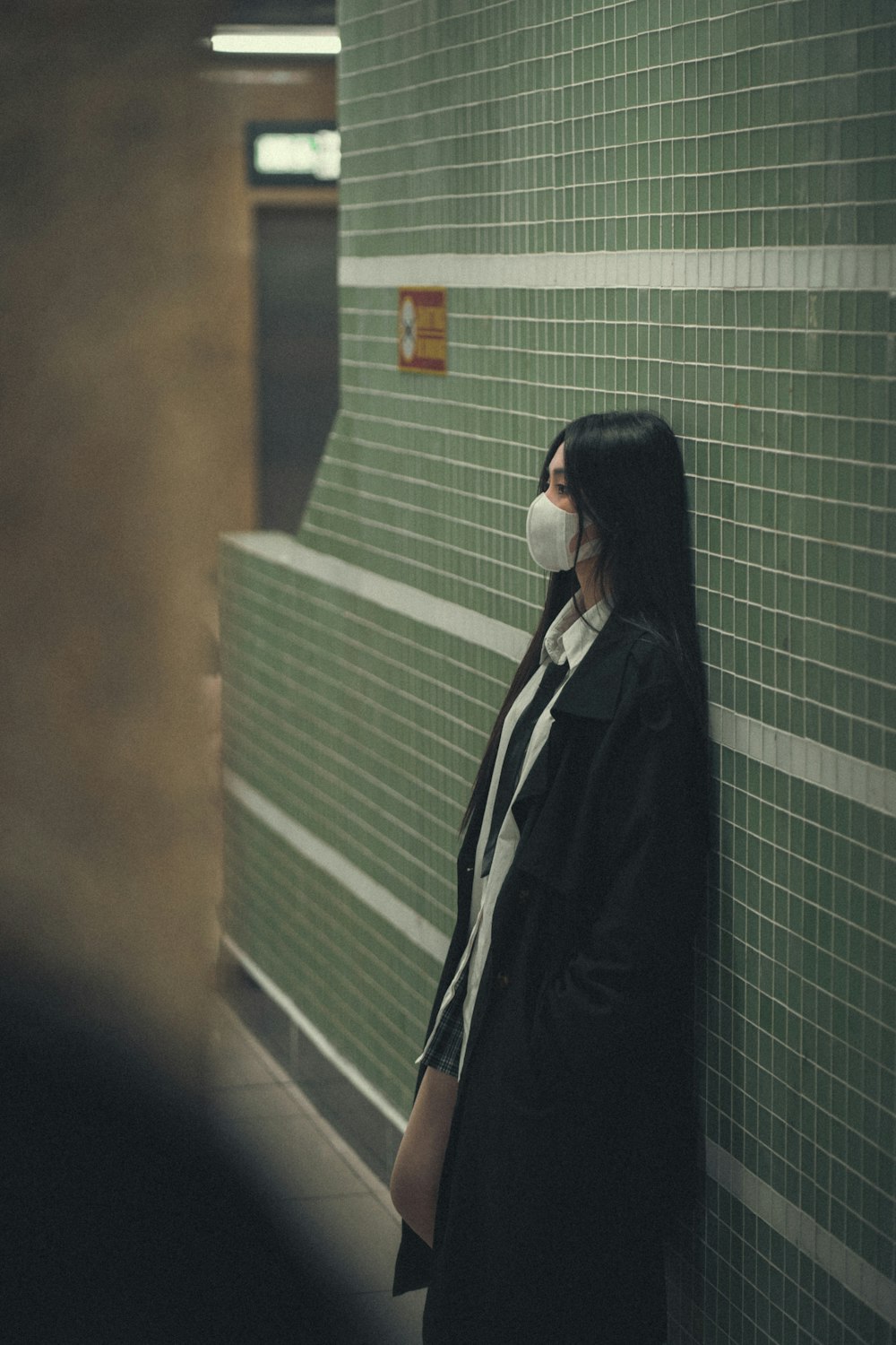 a woman wearing a face mask standing against a wall