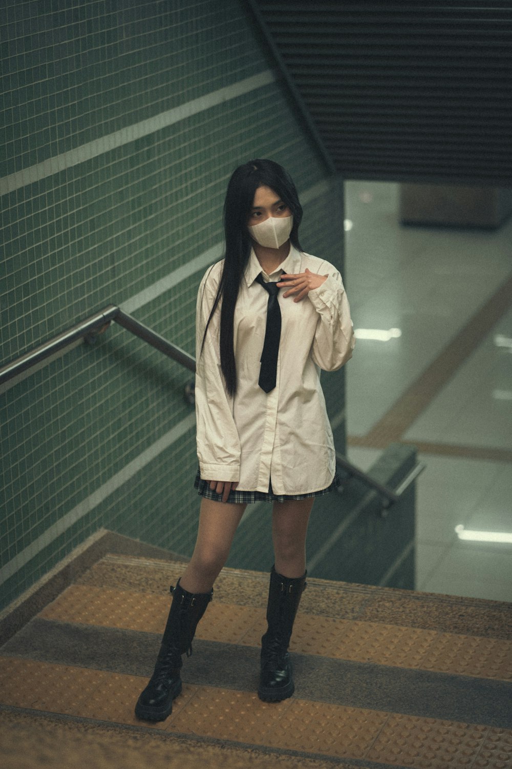 a woman wearing a mask and a tie standing on a set of stairs