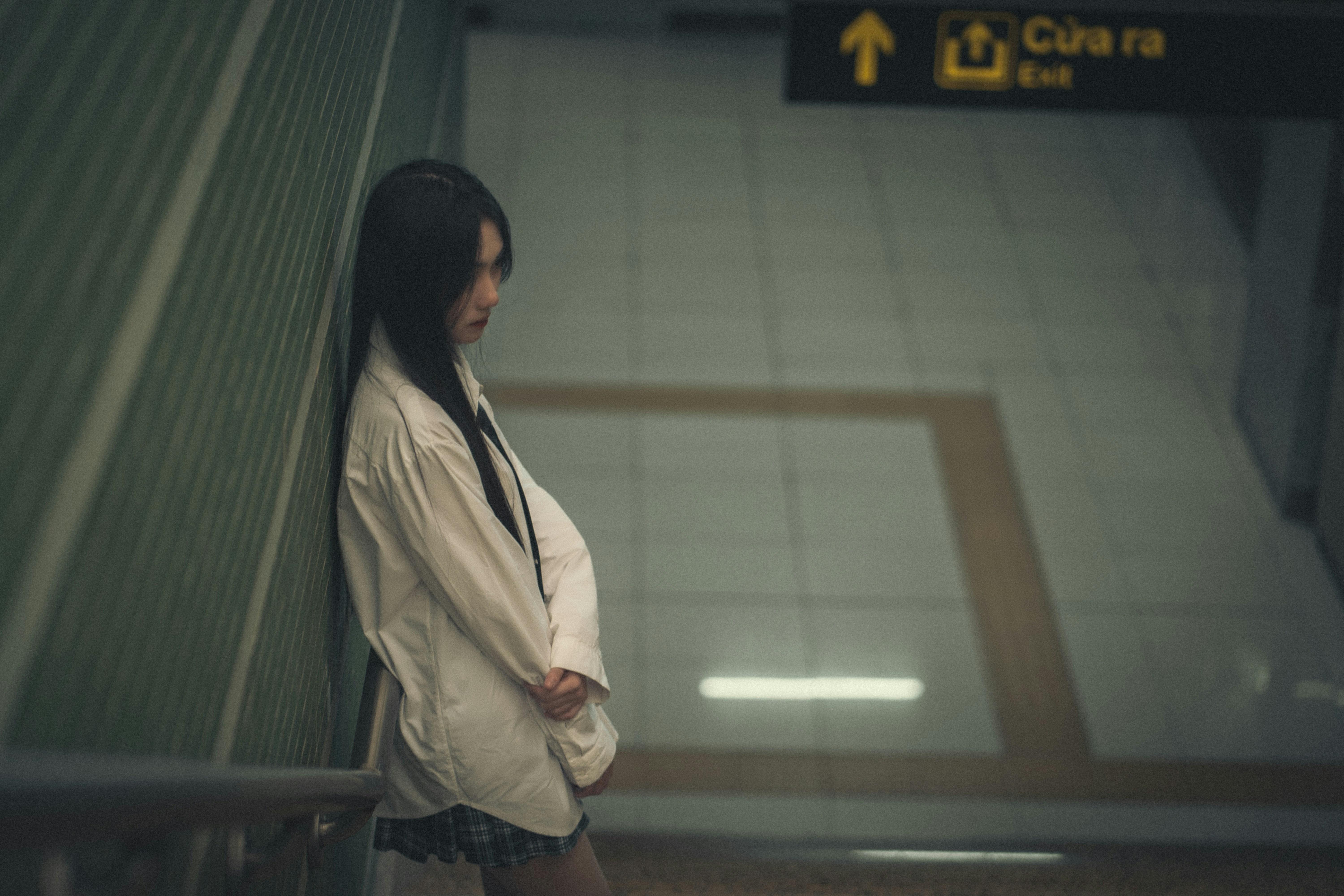 a woman leaning against a wall in a subway station