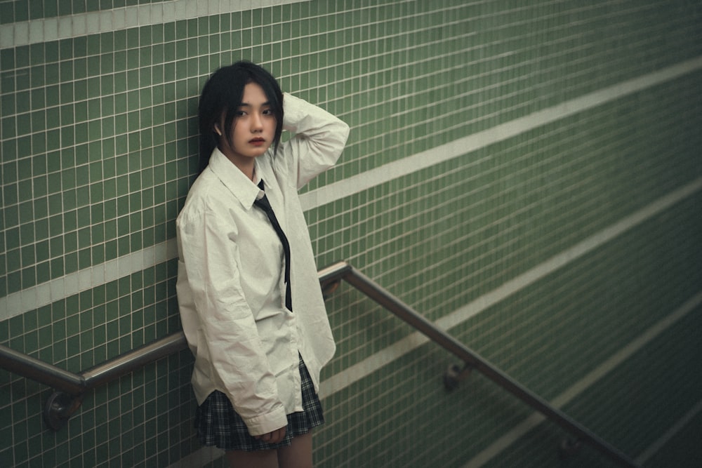 a woman leaning against a wall with her hand on her head