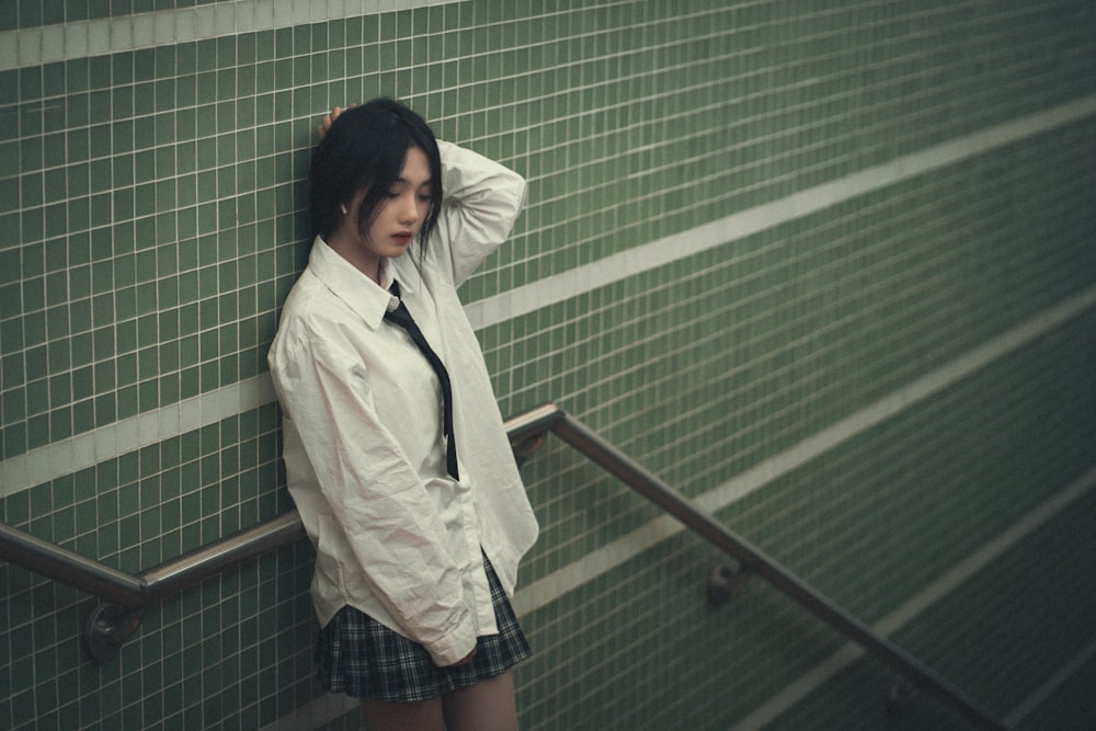 a woman leaning against a wall with her hand on her head