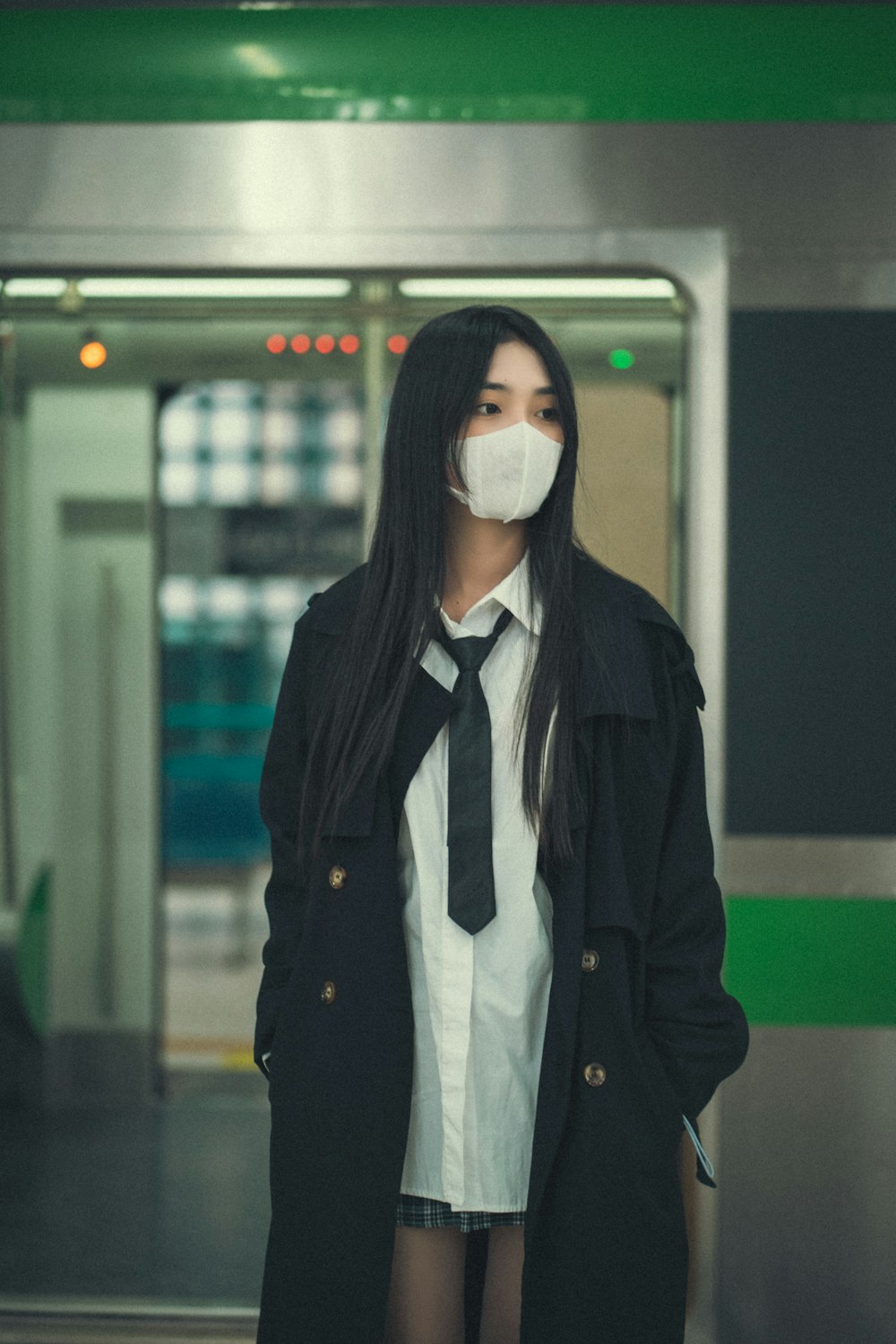 a woman wearing a face mask standing in a subway station