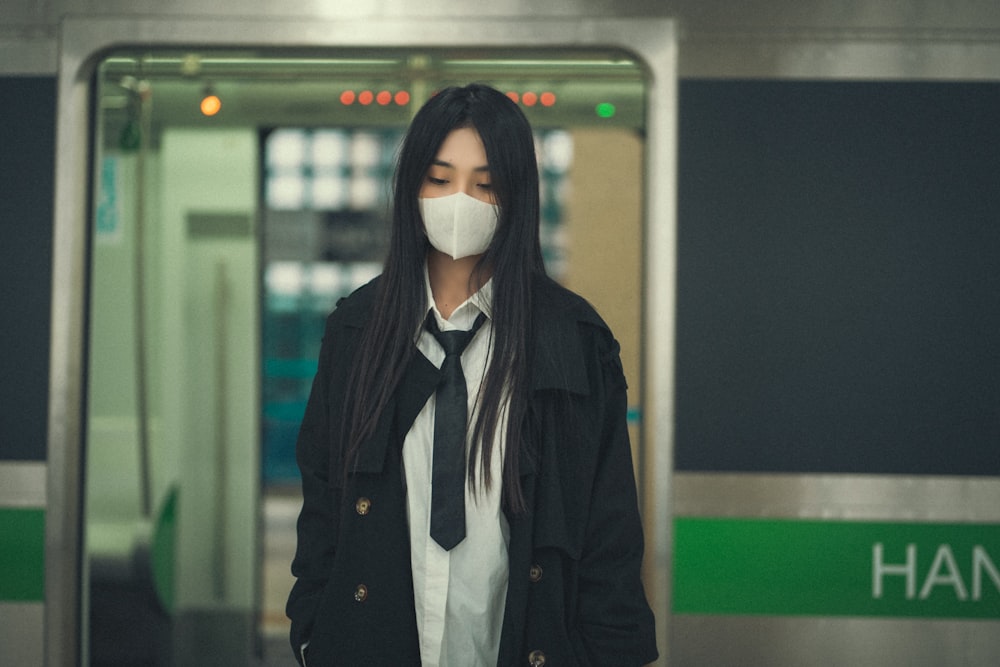 a woman wearing a mask standing in front of a train