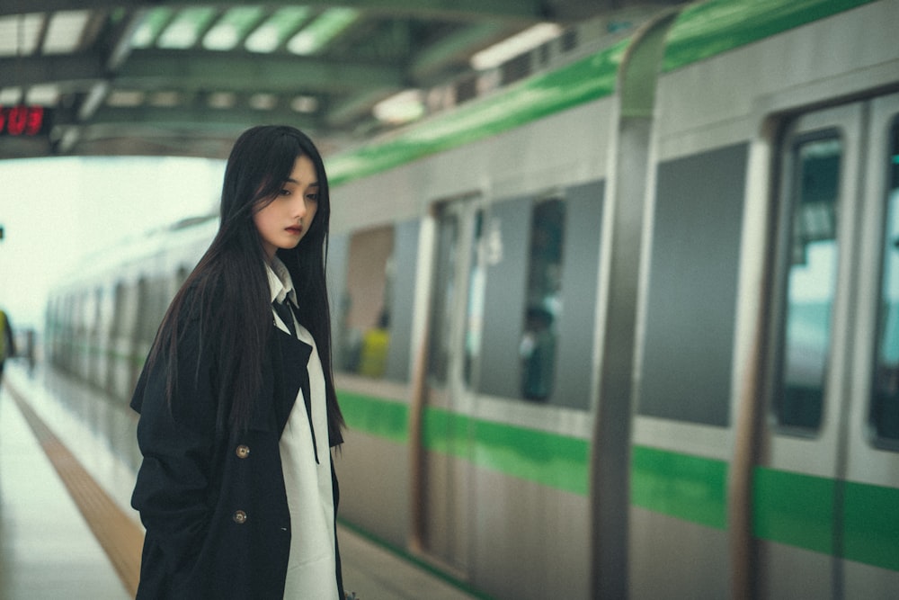 a woman standing in front of a train at a train station