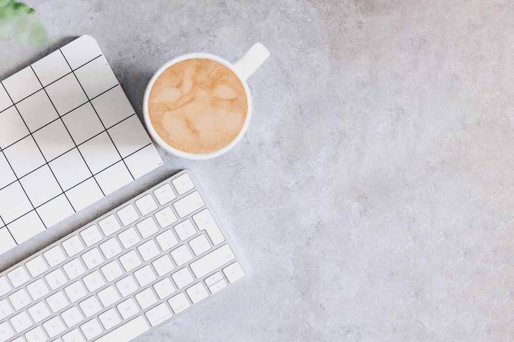 a cup of coffee next to a keyboard and mouse