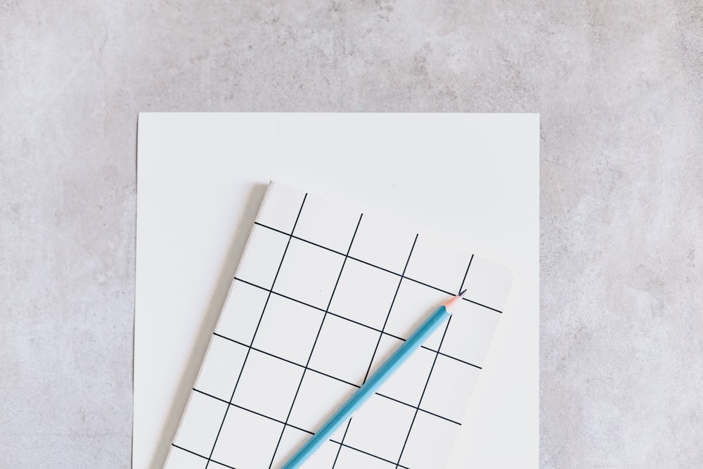 a blue pencil sitting on top of a piece of paper