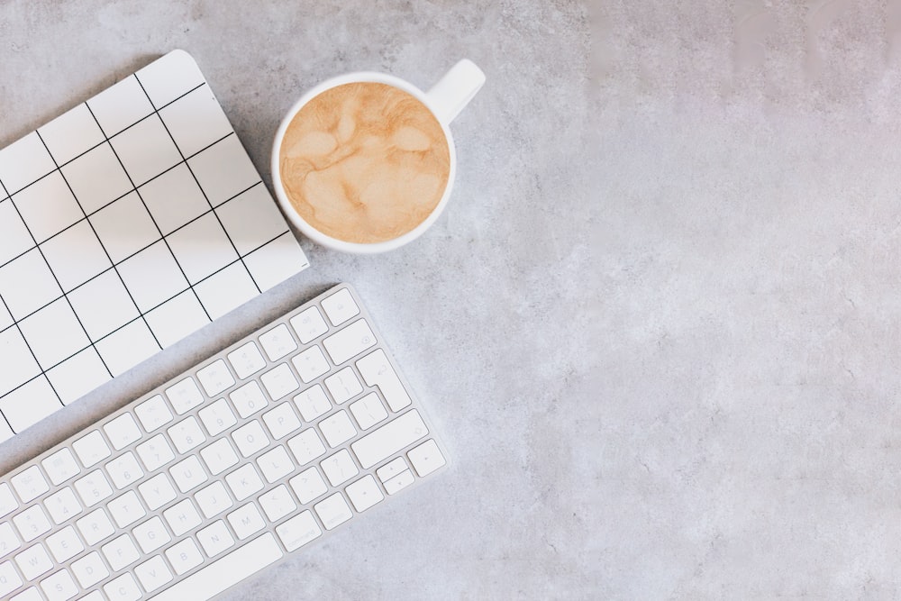 a cup of coffee next to a keyboard and mouse