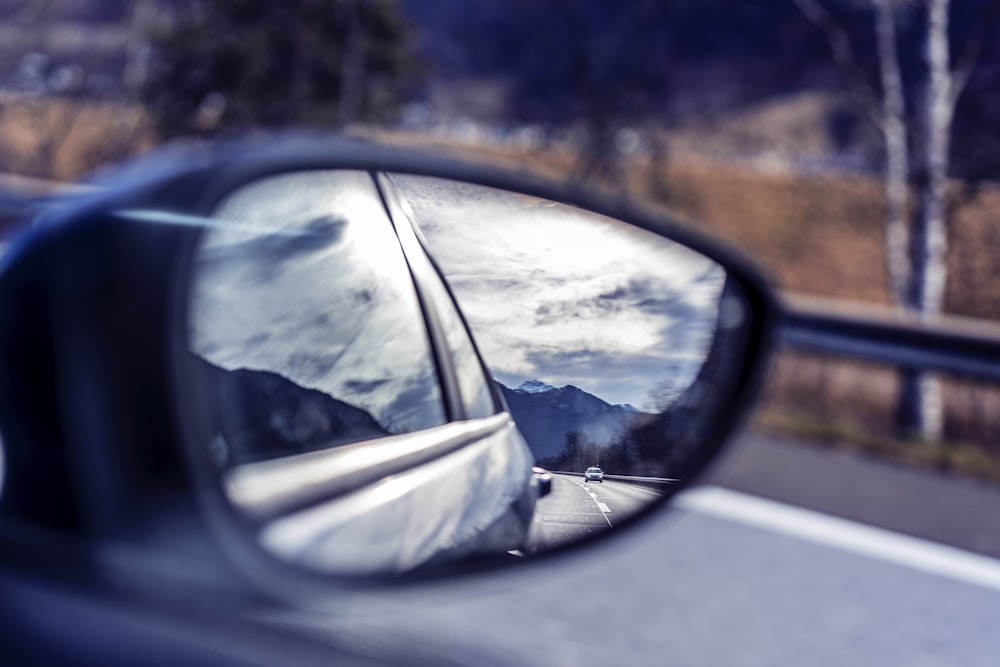 a car's side view mirror reflecting mountains in it