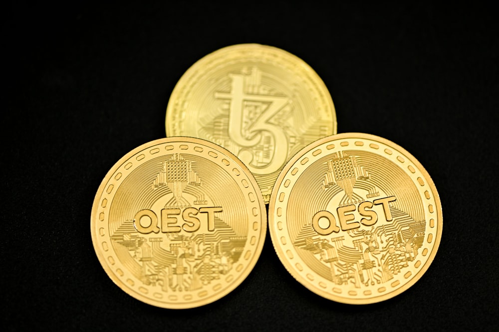 a close up of three gold coins on a black surface
