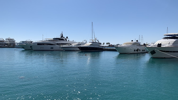 A yacht smoothly docking at a marina with a clear blue sky in the background.