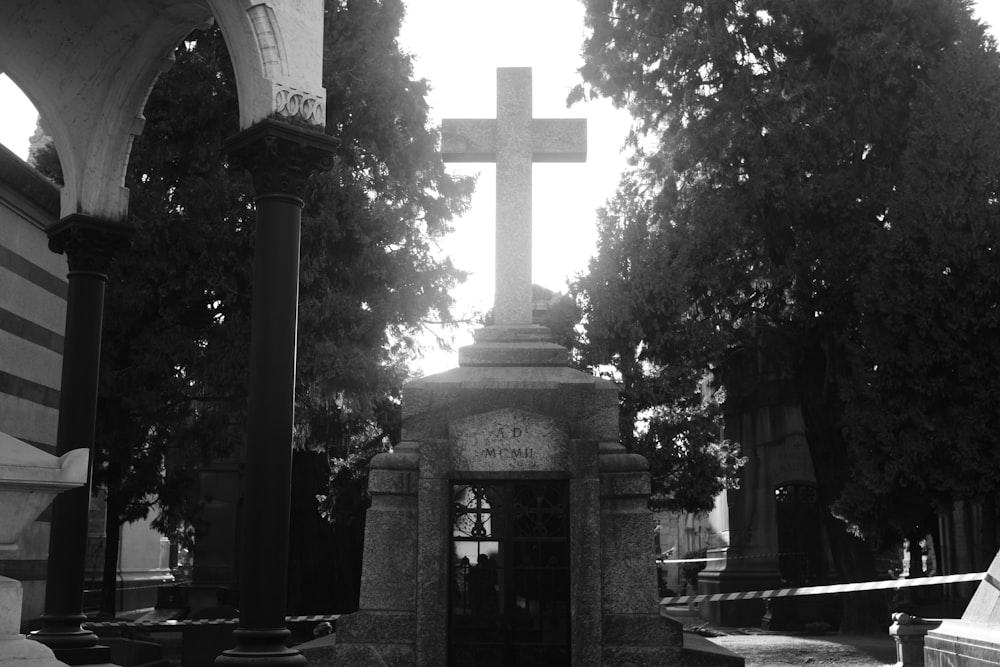 a black and white photo of a cross in a cemetery