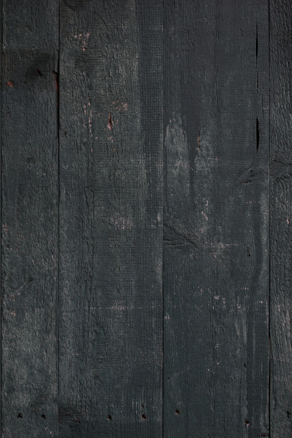 a black wooden wall with peeling paint on it