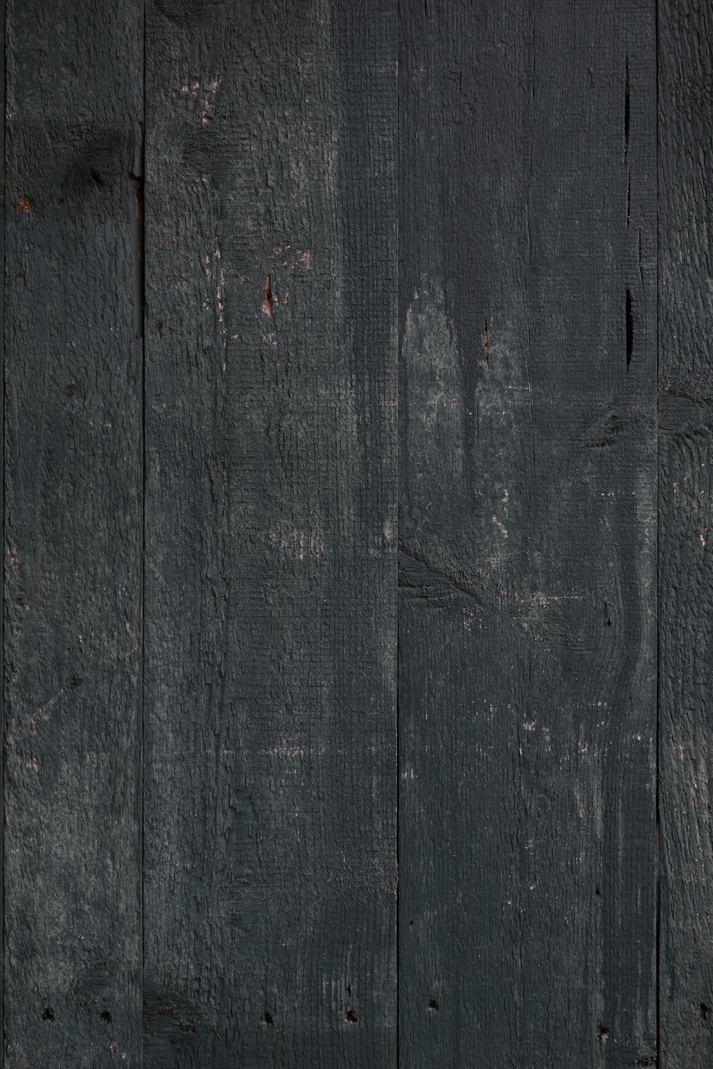 una pared de madera negra con pintura descascarada