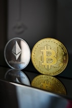 a bitcoin and ether coin sitting next to each other