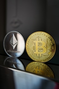 a bitcoin and ether coin sitting next to each other