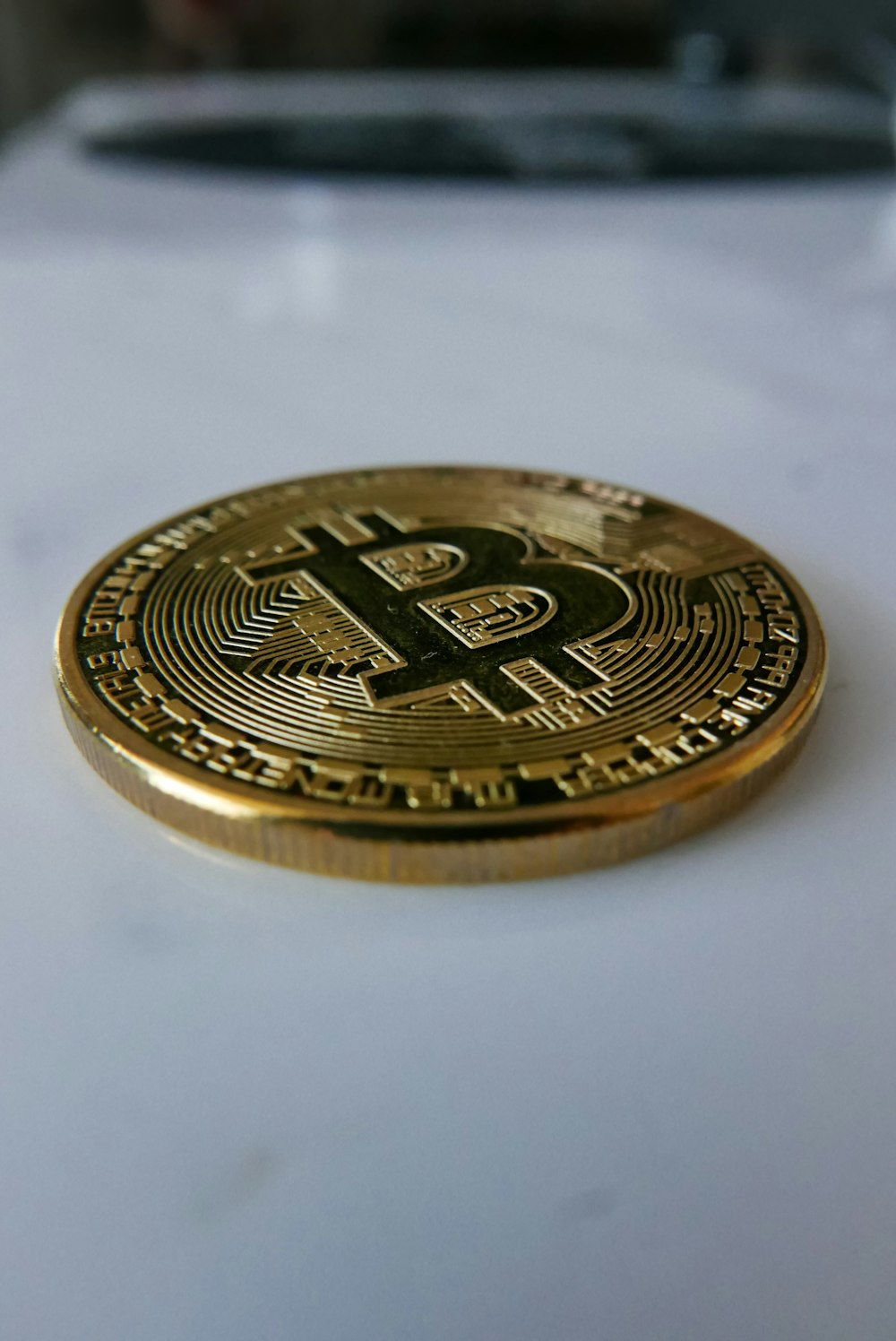 a golden bit coin sitting on top of a white table