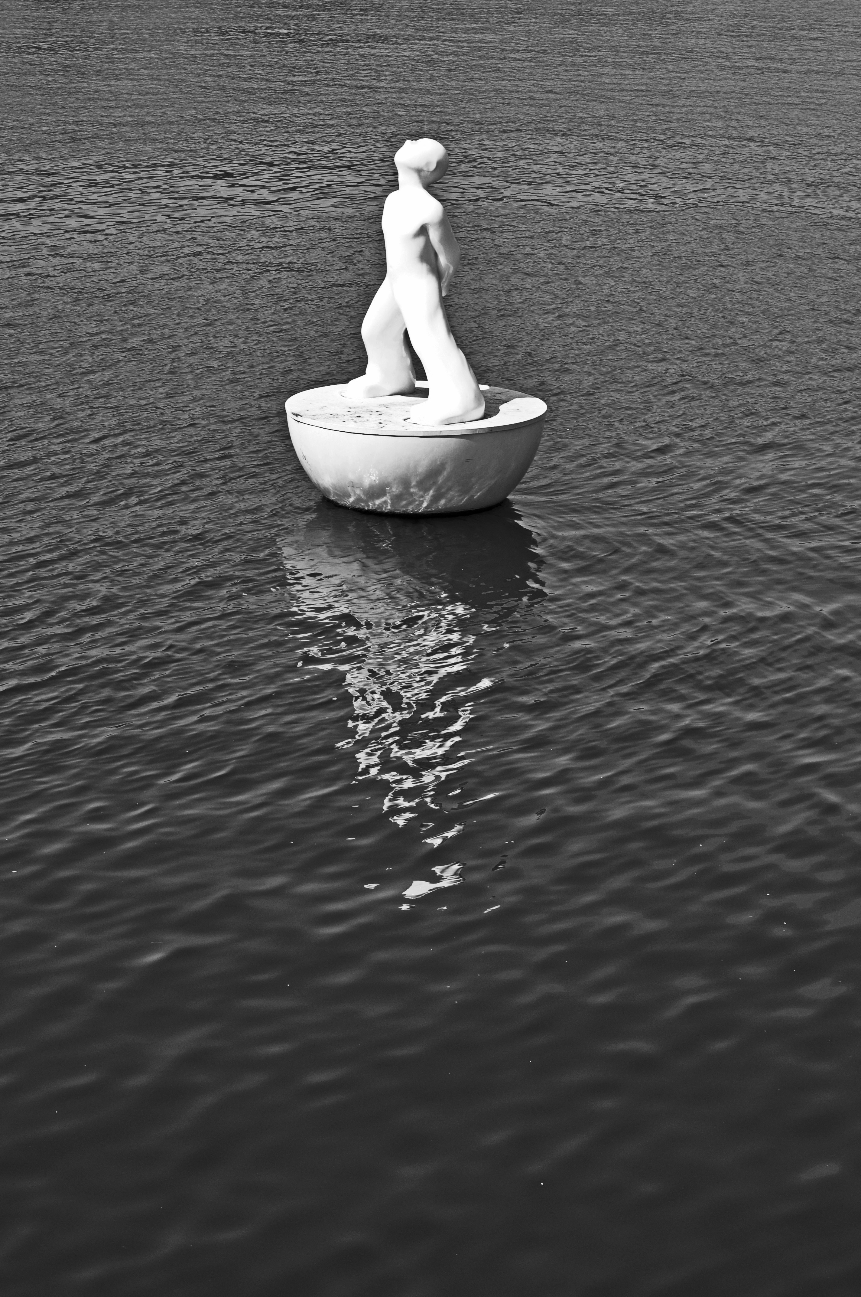 eine Statue eines Mannes, der auf einem Boot in einem Gewässer sitzt