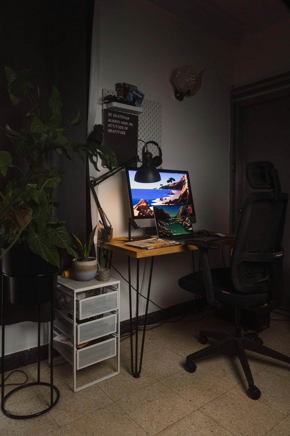a desk with a computer and a plant on it