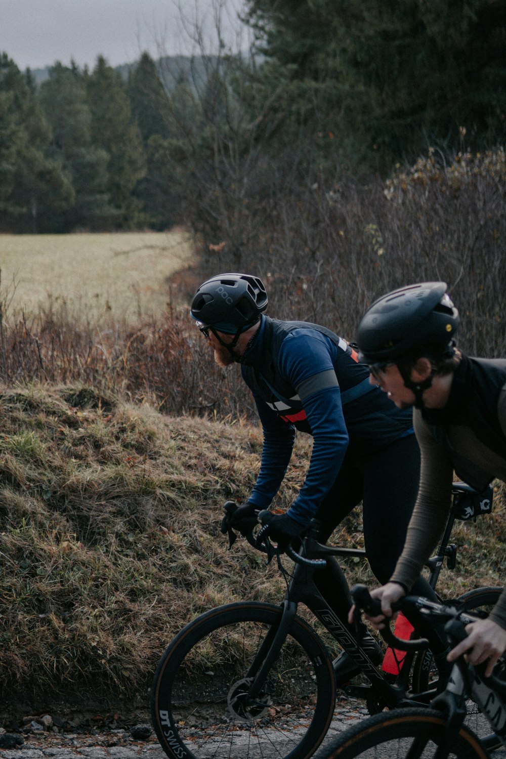 a couple of men riding bikes down a road