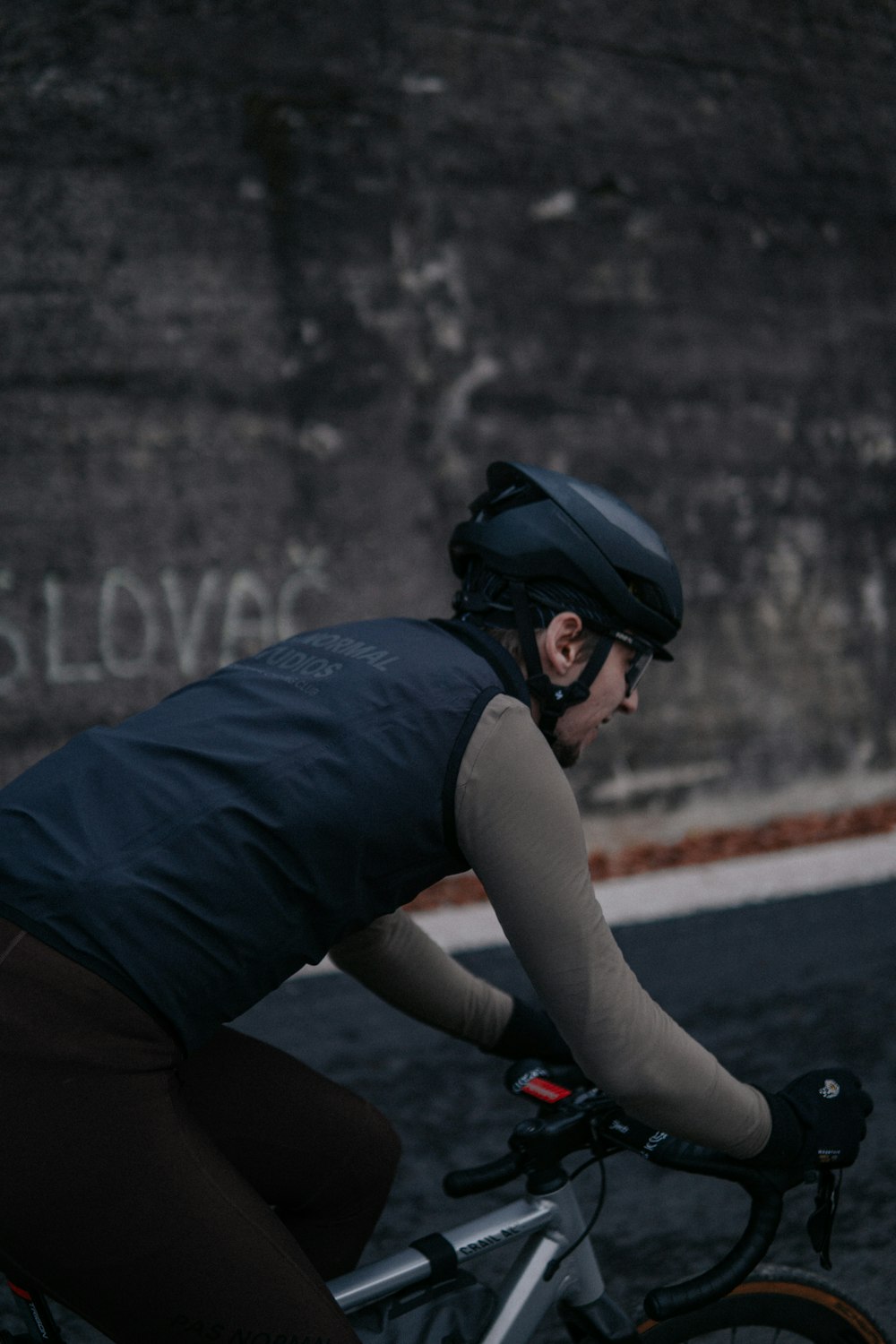 a man riding a bike down a street next to a wall