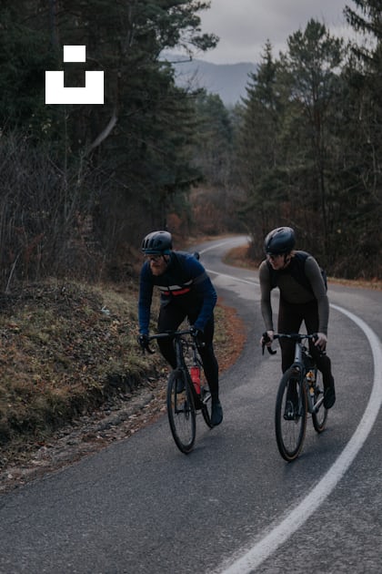Two bicyclists are riding down a winding road photo – Free Wellness ...