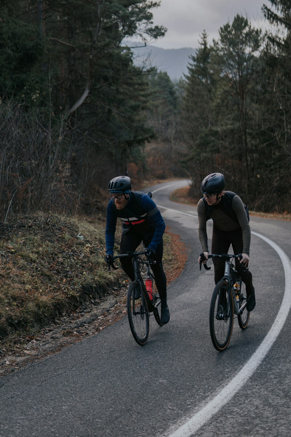 two bicyclists are riding down a winding road