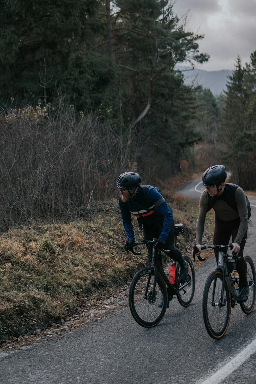 a couple of men riding bikes down a road