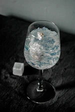 Artisan gourmet ice cubes glistening in a stylish glass on a wooden table.