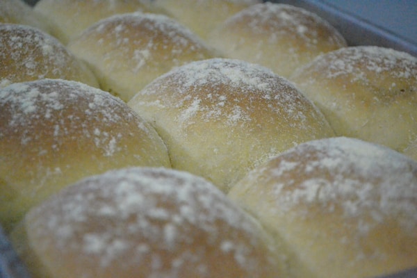 A pan filled with rolls covered in powdered sugar