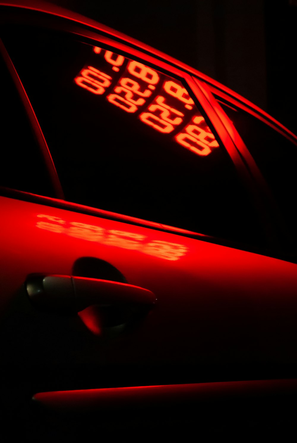 a close up of a red car with a speed limit sign