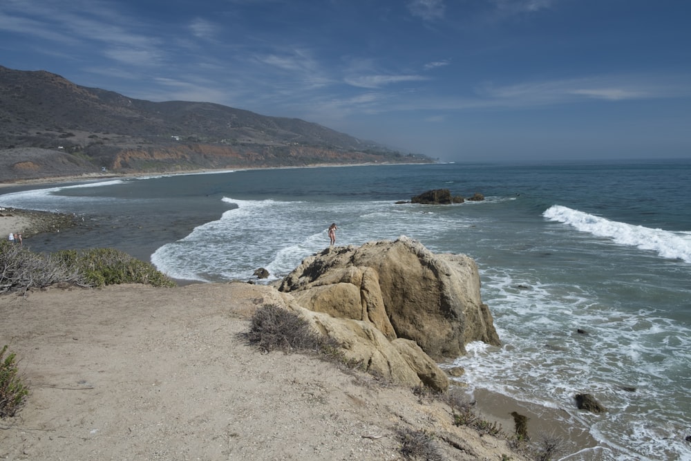 a person standing on top of a cliff near the ocean