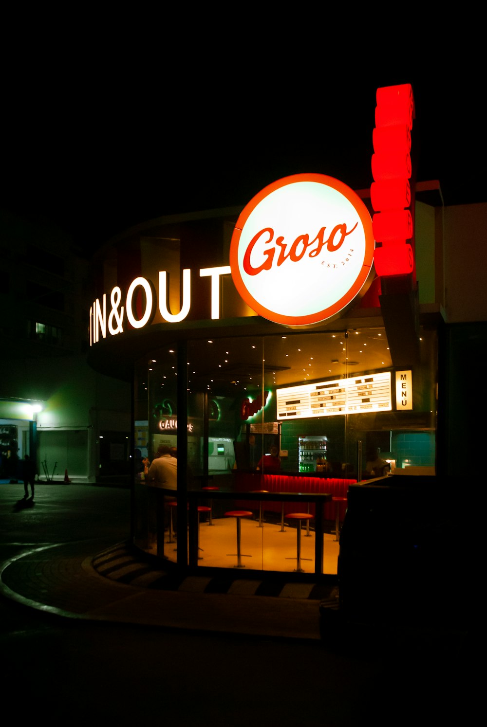 a group of people standing outside of a restaurant at night