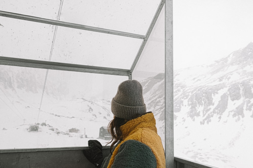 a person in a yellow jacket looking out a window