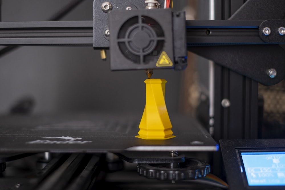Une imprimante 3D avec un cône jaune sur le dessus